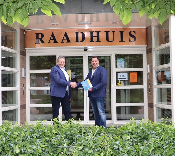 Fractievoorzitters De Leede en Strien tonen het bestuursakkoord en schudden elkaar de hand bij de hoofdingang van het Raadhuis